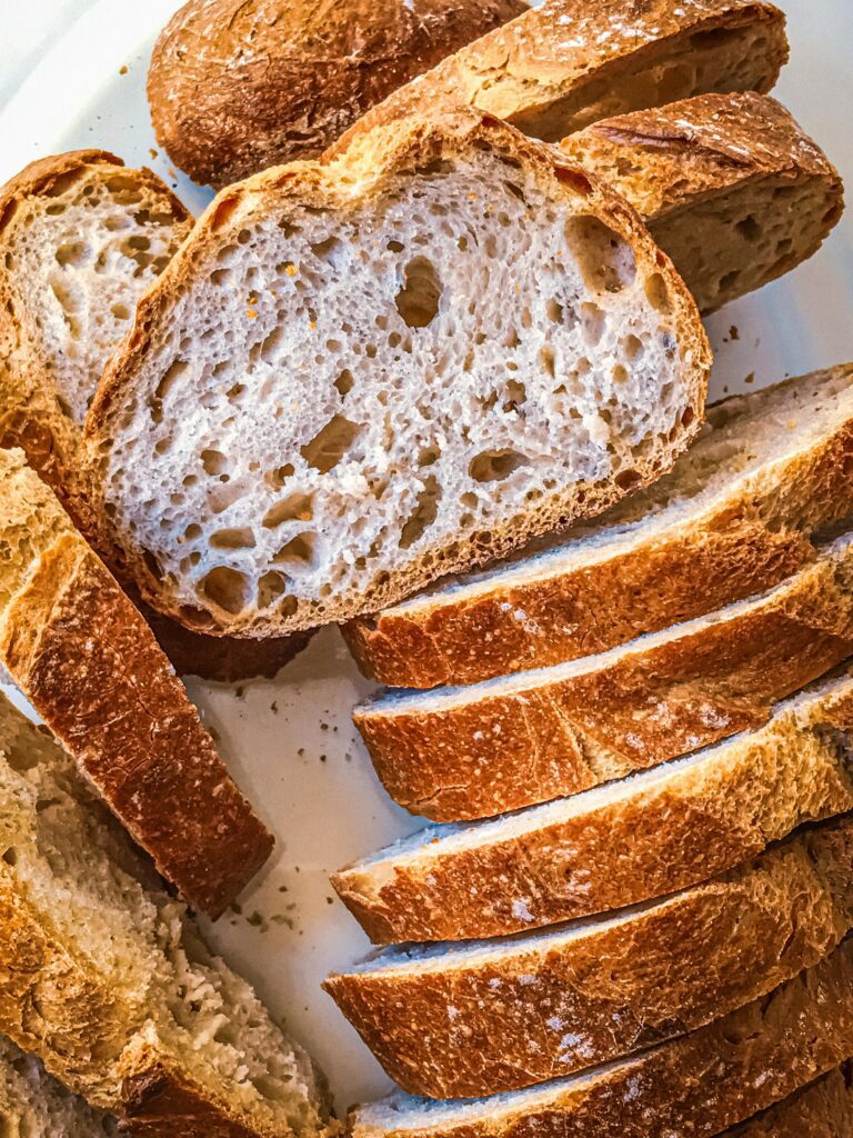 Homemade artisan bread loaf with a golden crust and airy interior, fresh out of the oven.